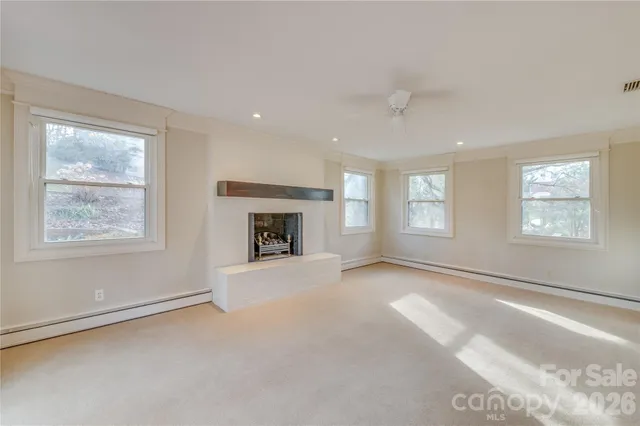 a view of an empty room with windows and a fireplace