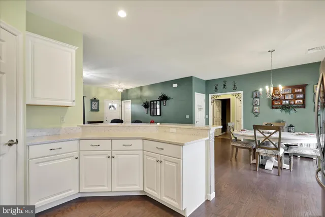 a spacious kitchen with white cabinets and chairs
