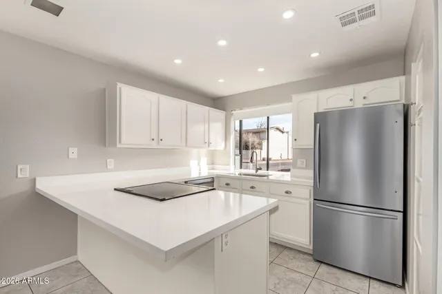 a kitchen with a refrigerator a sink and white cabinets