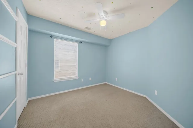 an empty room with a window and a fan