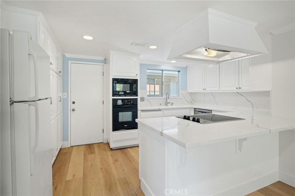 1176 Steele Drive Brea, CA 92821 - Photo 8 of 39 a kitchen with stainless steel appliances a stove a refrigerator a sink and white cabinets with wooden floor