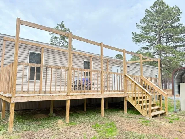 a view of a house with a backyard and wooden deck