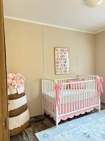 a view of a bedroom with wooden floor & a window