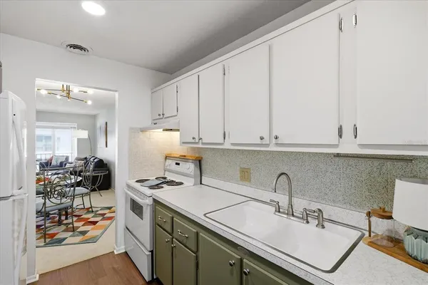 a kitchen with stainless steel appliances granite countertop a sink stove and white cabinets