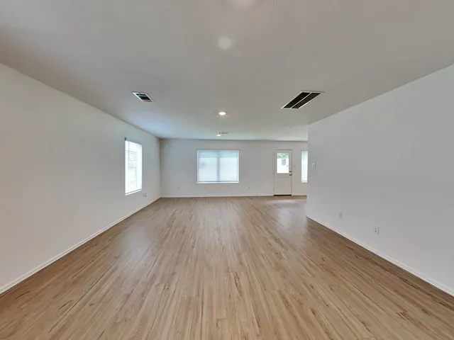 a view of empty room with window and wooden floor