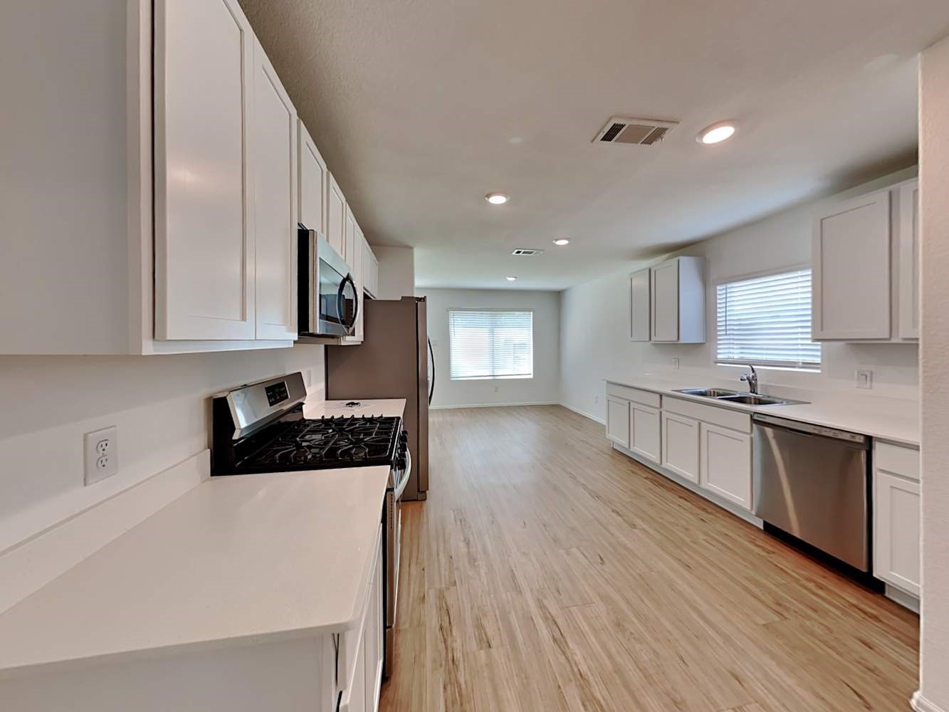 18606 Via Barletta Lane New Caney, TX 77357 - Photo 5 of 16 a kitchen with stainless steel appliances granite countertop a stove a sink and white cabinets with wooden floor