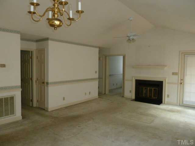 5608 Spring Pines Way Raleigh, NC 27616 - Photo 14 of 15 an empty room with a fireplace and chandelier