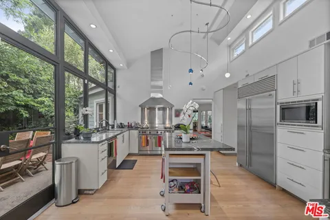 a kitchen with stainless steel appliances kitchen island granite countertop a stove and a large window