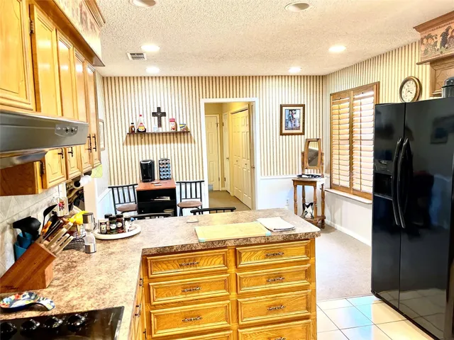 a room with stainless steel appliances kitchen island granite countertop a refrigerator a stove and a dining table with wooden floor