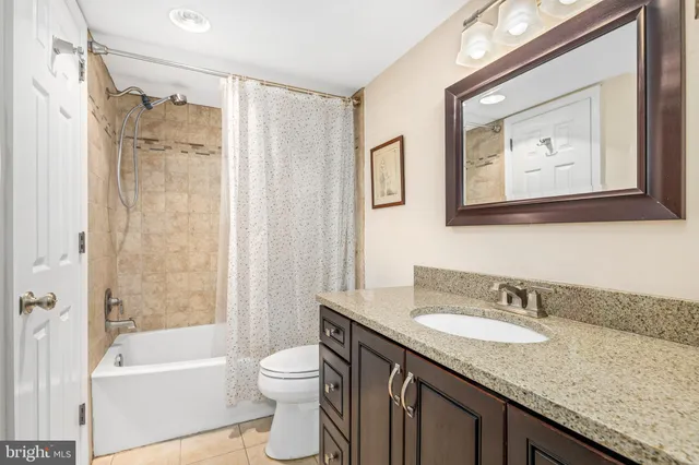 a bathroom with a granite countertop tub sink toilet and mirror