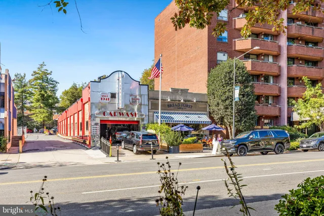 a front view of a multi story building with yard and sign board