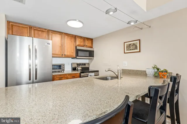 a kitchen with stainless steel appliances granite countertop a refrigerator a stove a sink a dining table and chairs with wooden floor