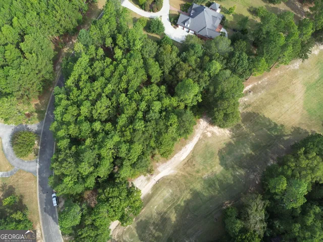 an aerial view of residential house with outdoor space and trees all around