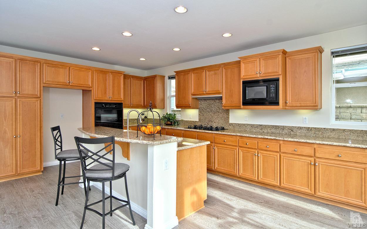 3522 Bridgehampton Way Camarillo, CA 93012 - Photo 10 of 52 a kitchen with stainless steel appliances granite countertop a stove top oven a sink a refrigerator with a dining table and chairs with wooden floor