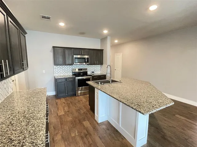 a kitchen with stainless steel appliances granite countertop a sink stove and refrigerator
