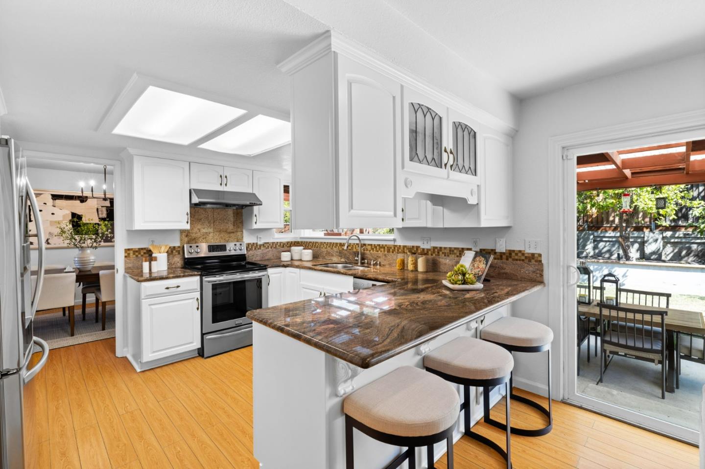 1386 Prada Court Milpitas, CA 95035 - Photo 9 of 36 a kitchen with stainless steel appliances granite countertop a stove top oven a sink a dining table and chairs with wooden floor