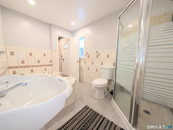 a spacious bathroom with a bathtub shower sink mirror and toilet