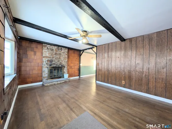 an empty room with wooden floor fireplace and windows