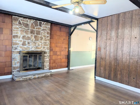 an empty room with wooden floor fireplace and window