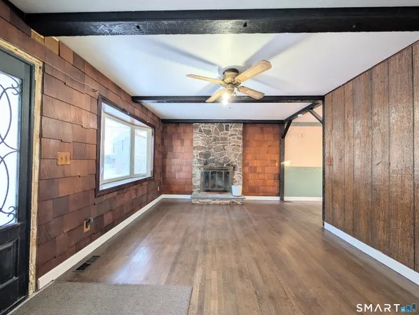 a view of an empty room with a window and wooden floor