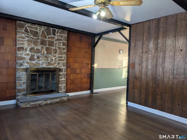 an empty room with wooden floor a fireplace and chandelier fan