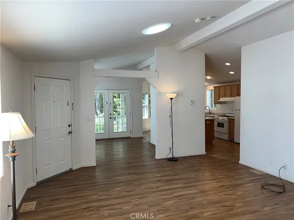 an empty room with wooden floor and a kitchen