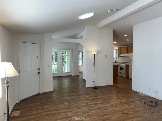 an empty room with wooden floor and a kitchen