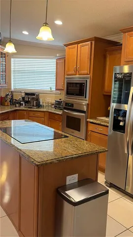 a kitchen with stainless steel appliances granite countertop a sink a stove a microwave a refrigerator a stove and island with wooden floor