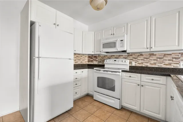 a kitchen with white cabinets and white appliances