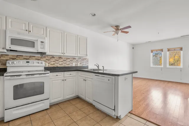 a kitchen with granite countertop white cabinets white stainless steel appliances with a sink and dishwasher