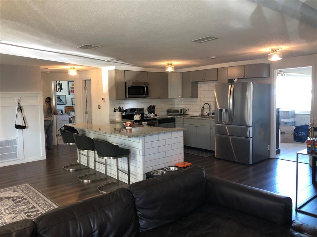 6425 Reno Avenue New Port Richey, FL 34653 - Photo 5 of 17 a kitchen with stainless steel appliances granite countertop a refrigerator a stove a sink a dining table and chairs with wooden floor