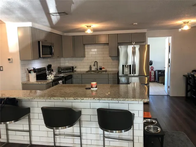 a kitchen with stainless steel appliances granite countertop a stove top oven a sink a dining table and chairs