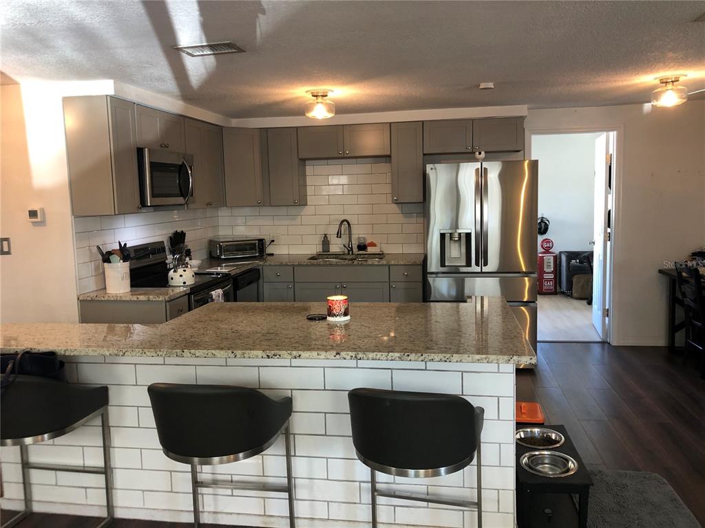 6425 Reno Avenue New Port Richey, FL 34653 - Photo 9 of 17 a kitchen with stainless steel appliances granite countertop a stove top oven a sink a dining table and chairs