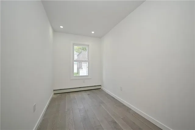 an empty room with wooden floor and window
