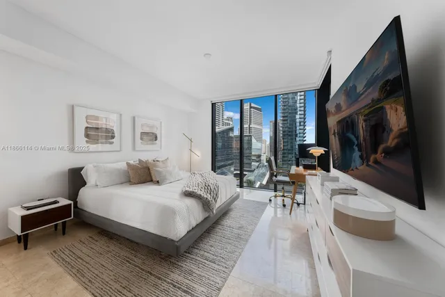 a bedroom with a large bed a flat tv screen and a couch