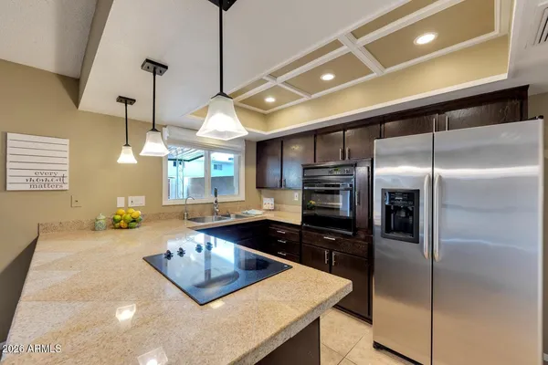 a kitchen with a refrigerator a sink a counter space cabinets and appliances
