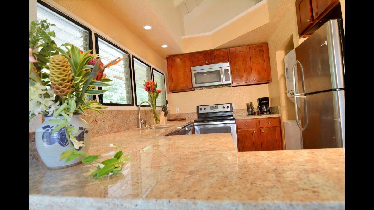 4480 Ka Haku Road, Unit 208 Princeville, HI 96722 - Photo 15 of 28 a kitchen with stainless steel appliances wooden floor and a refrigerator