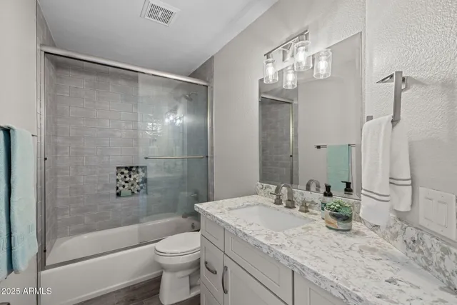 a bathroom with a granite countertop sink toilet and shower