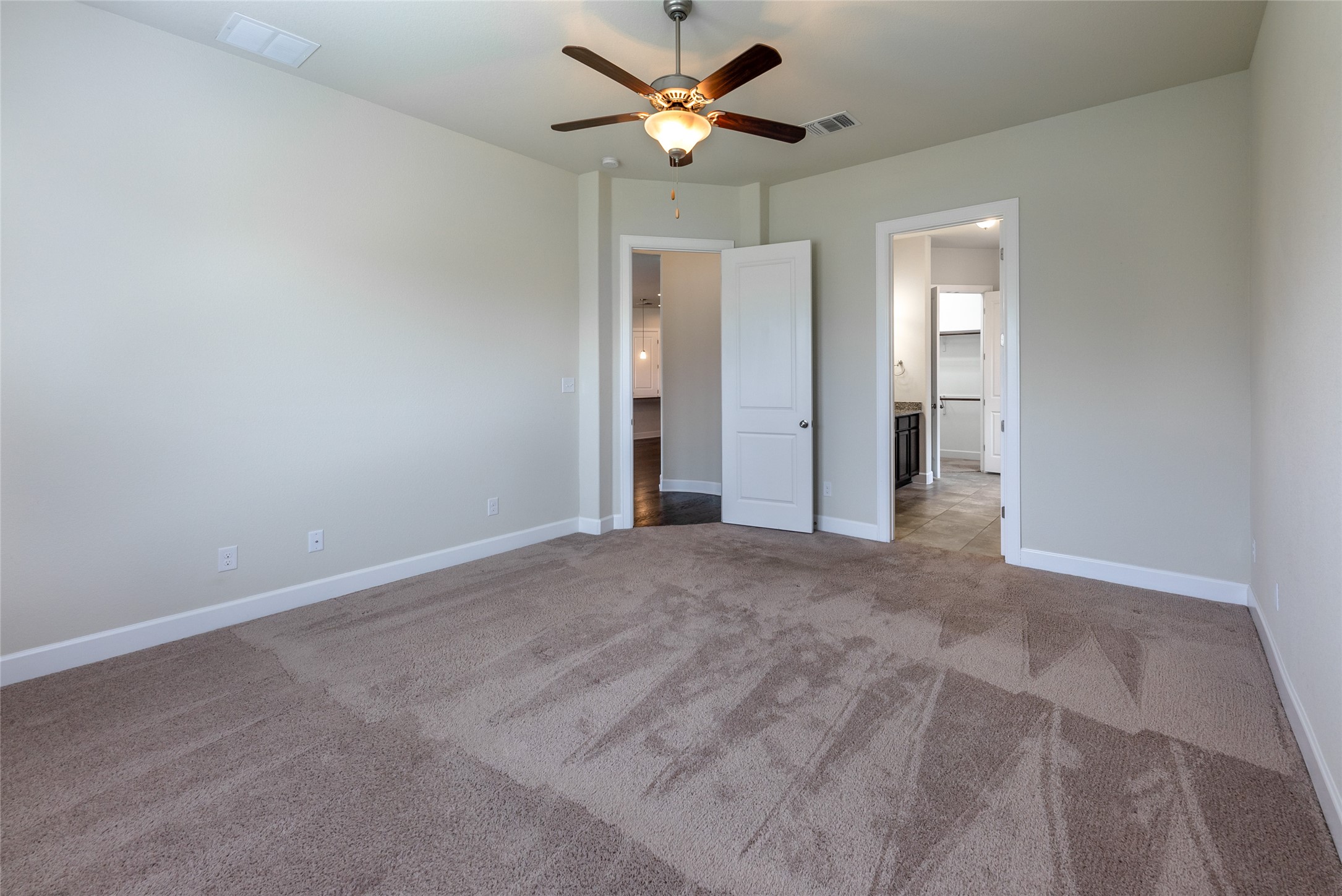 3043 Hidalgo Loop Round Rock, TX 78665 - Photo 11 of 34 Unfurnished bedroom featuring ensuite bath, ceiling fan, and light colored carpet