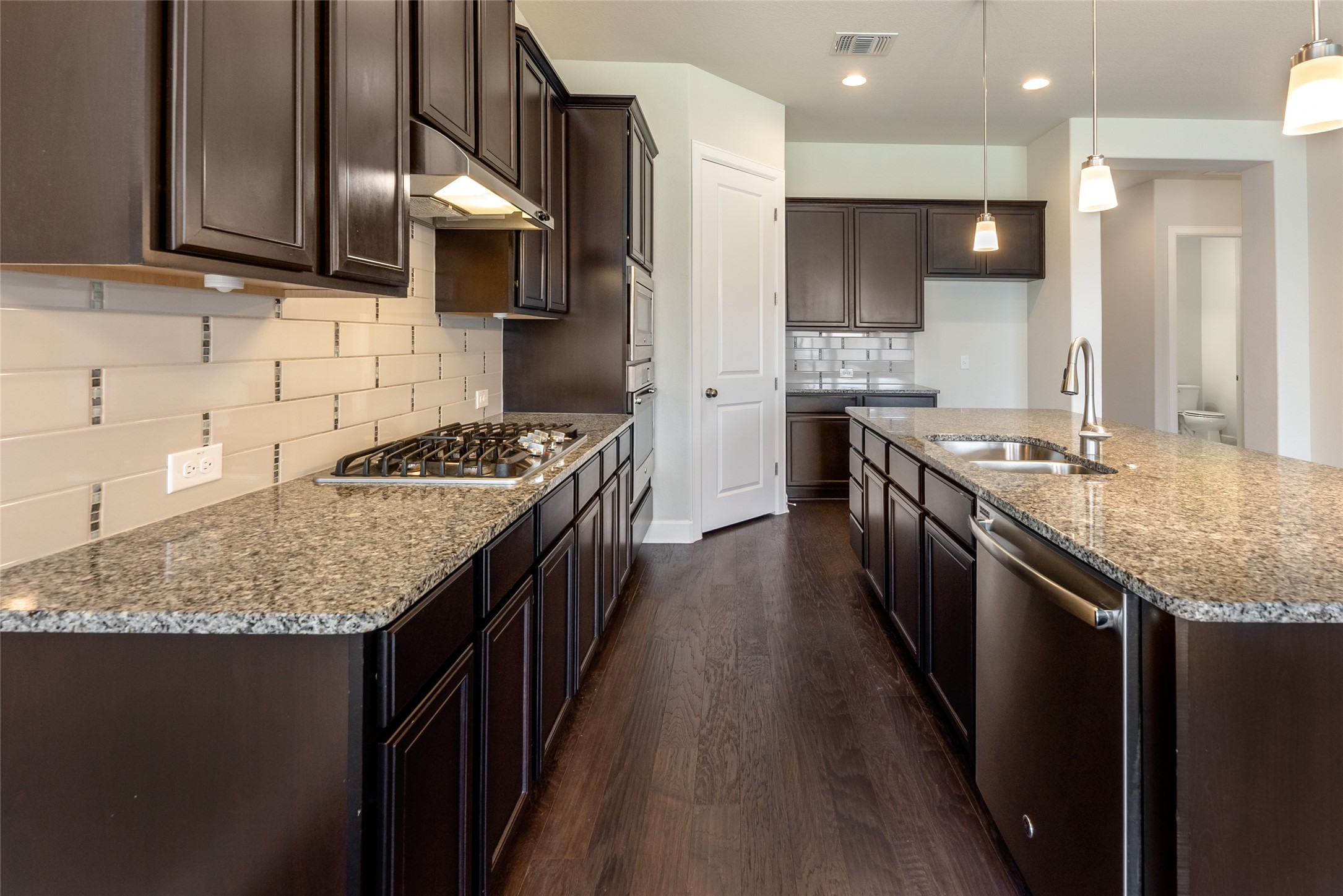 3043 Hidalgo Loop Round Rock, TX 78665 - Photo 4 of 34 Kitchen featuring dark wood finish cabinetry, light stone countertops, dark wood finished floors, stainless steel appliances, and tasteful backsplash