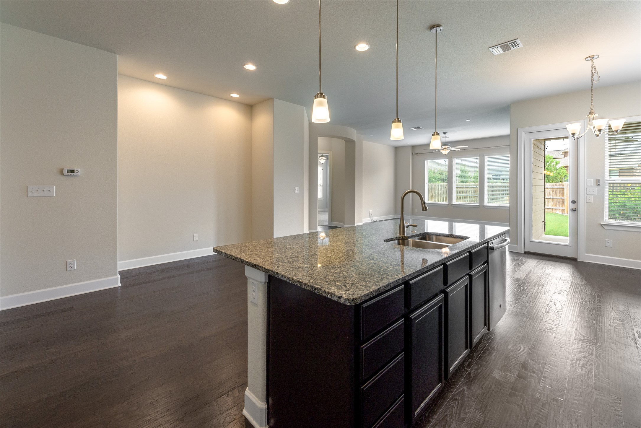 3043 Hidalgo Loop Round Rock, TX 78665 - Photo 34 of 34 Kitchen featuring dark stone countertops, dark wood-style floors, an island with sink, open floor plan, and arched walkways