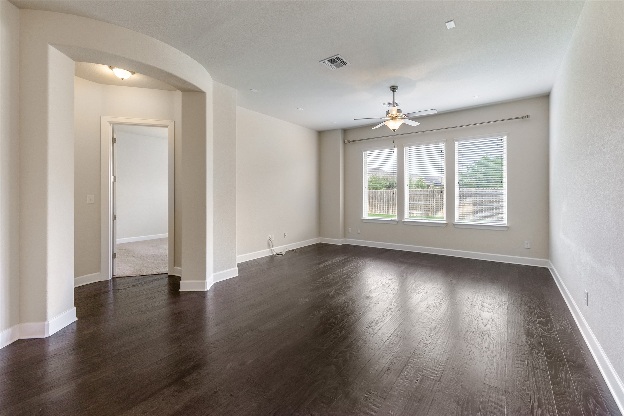 3043 Hidalgo Loop Round Rock, TX 78665 - Photo 5 of 34 Spare room with arched walkways, dark wood-style flooring, and a ceiling fan