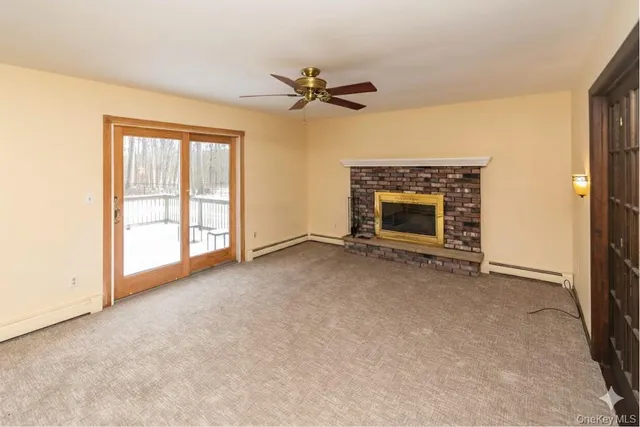 an empty room with windows fireplace and a ceiling fan