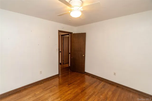 an empty room with wooden floor and fan