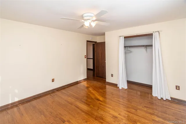 an empty room with closet and a ceiling fan