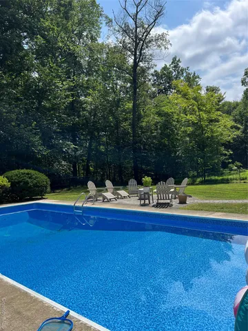 a view of swimming pool with lawn chairs and plants