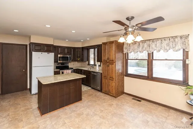 a kitchen with kitchen island a large counter top space stainless steel appliances and a large window