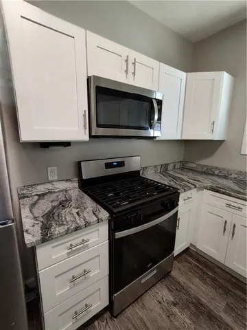 a kitchen with stainless steel appliances granite countertop a refrigerator a stove a sink and a microwave