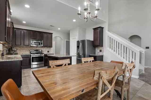 a kitchen with stainless steel appliances granite countertop a stove top oven a sink dishwasher a dining table and chairs with wooden floor