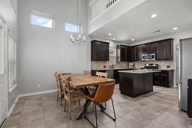 a kitchen with a dining table chairs and refrigerator